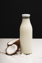 coconut halves, flakes, and bottle of milk on white surface isolated on black, stock image
