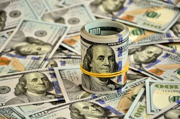 A roll of dollars on a background  of hundred-dollar bills. The concept of wealth and prosperity in business.