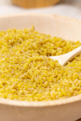 bulgur in a wooden bowl on the background of a wooden table, rustic style. Bulgur wheat grains