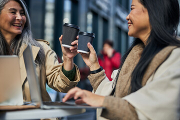 Cheerful female friends toasting with coffee in outdoors cafe