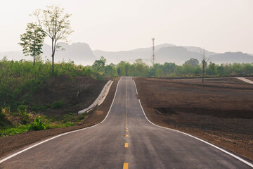 A long straight road leading towards a mountain