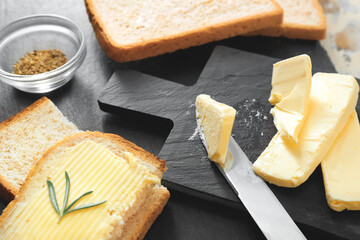 Chopping board with tasty bread, butter and spices on table