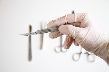 Surgery knife holding on the white background, studio shot. Operation equipment.
