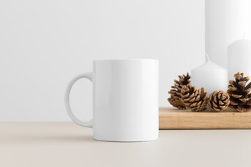 White mug mockup with candles on a table. Christmas decoration