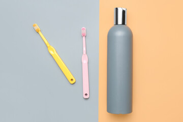 Shower gel and toothbrushes on color background