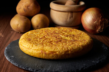 A closeup of a fresh tasty Spanish omelette and the ingredients on the background, a traditional dish from Spain