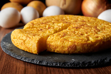 A closeup of a fresh tasty Spanish omelette and the ingredients on the background, a traditional dish from Spain