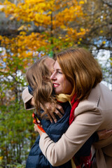 Happy mother and daughter 7-9 years old in autumn Park, mother hugs daughter, the concept of a happy family, mother-child relationship, mother's Day, motherhood happiness