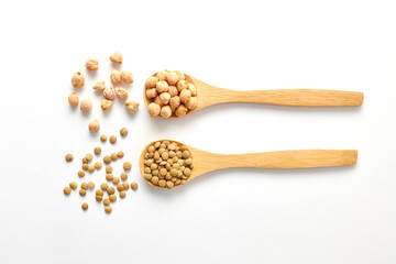 A pile of chickpeas on a wooden spoon and scattered on the white surface