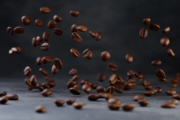 Grains of roasted coffee falling on gray stone background. Levitation coffee beans. Shallow depth...