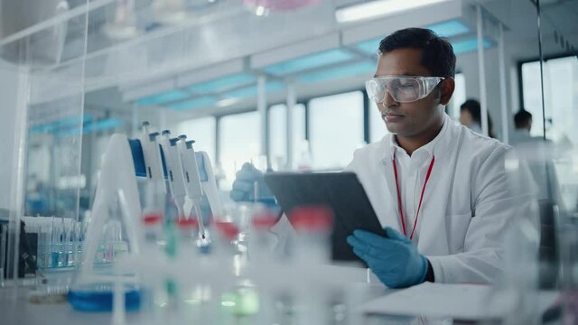 Medical Research Laboratory: Portrait of a Handsome Male Scientist Using Digital Tablet Computer to Analyse Data. Advanced Scientific Lab for Medicine, Biotechnology, Microbiology Development