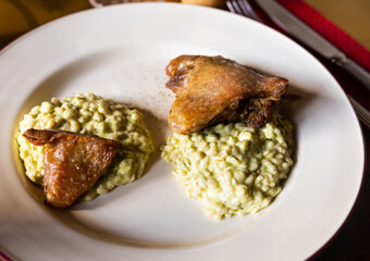 dish duck leg with green perlotto served on a white plate