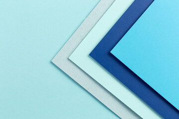 Material design blue background. Craft paper sheets are folded in different ways. A photo.