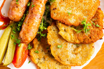 potato pancakes with fried sausages on a white plate