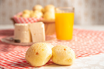 Cheese bread from Brazil. Cheese bread, Minas cheese and orange juice on a table with red and white checked tablecloth, selective focus.