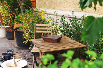 empty bread bin street cafe without people with dirty white dishes on wooden table with cutlery