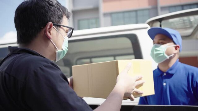 Asian blue delivery man wearing protection mask and medical rubber gloves send a package to customer on before deliver cargo. 4k resolution
