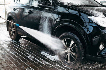 Woman washing his car in a self-service car wash station.Car wash self-service. 