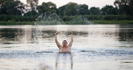 man swims in the river at sunset