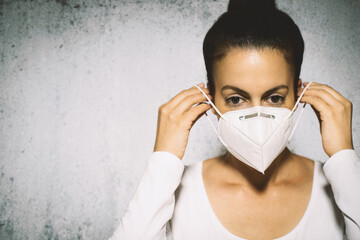 Portrait of young woman putting medical mask on.