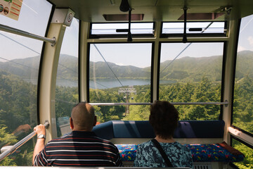cable cart passengers look over beautiful view on nature green hills and lake old couple in japan