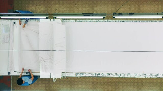 Top view of factory staff smoothing down fabric