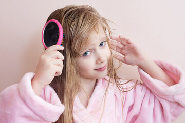 little girl combs her hair after a shower
