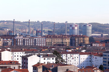 Obraz premium Vista de Avilés, ciudad industrial de Asturias en el norte de España con las chimeneas detrás de la población urbana
