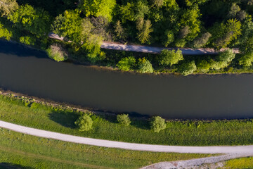 Road next to a river under trees of a forest in Munich, Thalkirchen. Aerial drone shot, bird view.