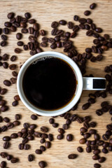 Cup of coffee with beans on wooden table - Top View