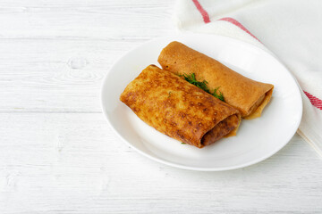 Two fried russian pancakes on white wooden table