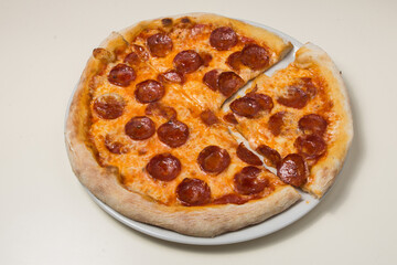 Pizza salami diavola with red onion basil and chili pepper.