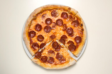Pizza salami diavola with red onion basil and chili pepper.