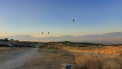Hot air balloons in the blue sky in the morning over a valley in Turkey.