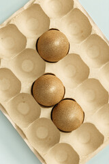 Painted Easter eggs gold colored in eggs box. Minimal easter concept. Beige monochrome photography.