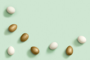 Painted Easter eggs white and gold colored on light green paper. Minimal easter concept. Top view spring holiday