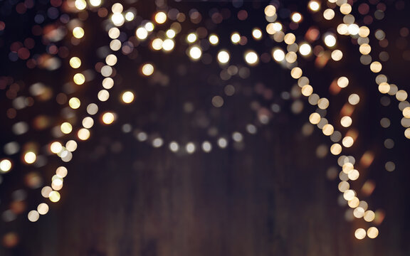 Abstract hanging Christmas, New Year background of fairy lights and dark blurred bokeh backdrop.