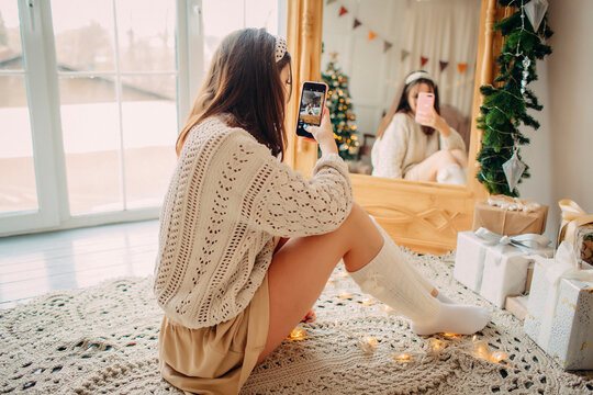 girl taking a photo with cell phone in christmas decorated room