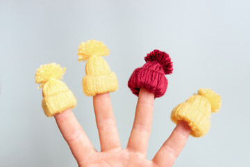 A small knitted hat is put on the fingers. The concept of winter, warm clothes and Christmas holidays.