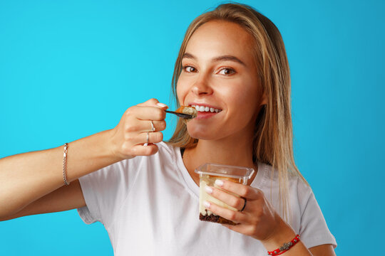 Beautiful young woman eating yogurt with a spoon
