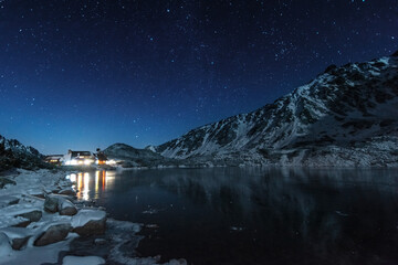 Starry sky in winter Polish Tatras near a mountain lake covered with ice