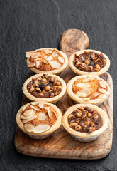 Christmas mini mince pie on wooden board on black stone background