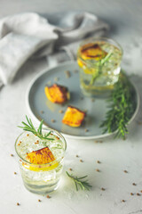 Two glasses of Charred Lemon, Rosemary and Coriander Gin and Tonic is a flavors are perfectly balanced refreshing cocktail. on light background, close up