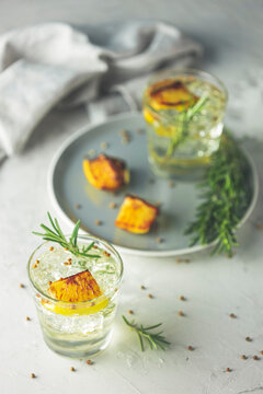 Two glasses of Charred Lemon, Rosemary and Coriander Gin and Tonic is a flavors are perfectly balanced refreshing cocktail. on light background, close up