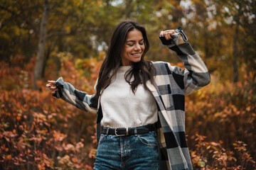 Beautiful happy woman dancing while strolling in autumn forest
