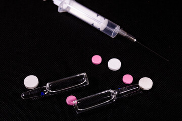 Syringe and pills on a black background. Healthcare and medicine concept