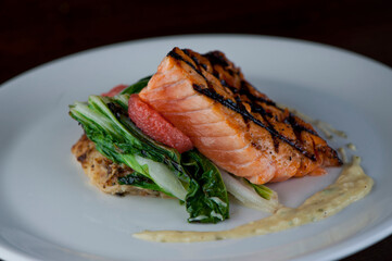 Salmon steak. Salmon grilled in olive oil, topped with almonds, scallions and Italian parsley. Served with garlic Brussel sprouts. Classic American restaurant or French bistro entree.