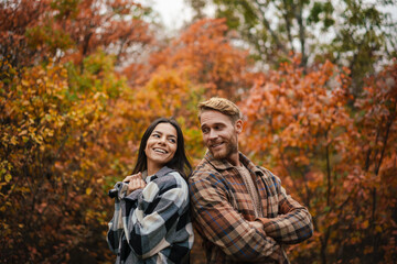 Beautiful happy couple smiling while standing back to back in forest
