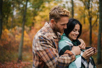 Romantic happy couple drinking tea and hugging while having picnic