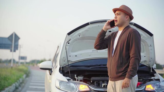Asian man has broken down car on the road he talking on phone to call someone to help or mechanics car service. 4k resolution.